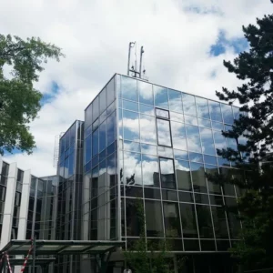 Immeuble moderne en verre avec arbres autour.