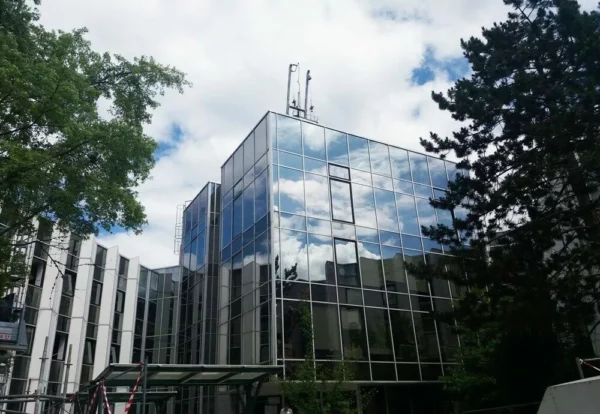 Immeuble moderne en verre avec arbres autour.