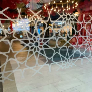 Motifs géométriques blancs sur une vitre de magasin.