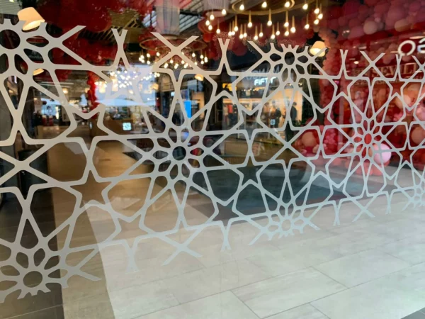 Motifs géométriques blancs sur une vitre de magasin.