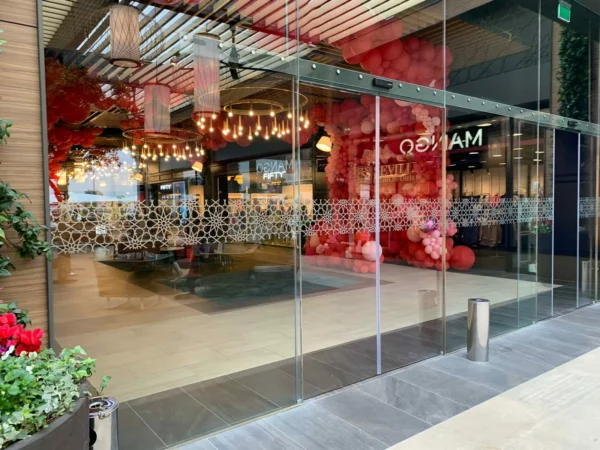 Entrée vitrée d'un magasin avec décorations lumineuses.
