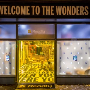 Devanture lumineuse de magasin avec affiches musicales.