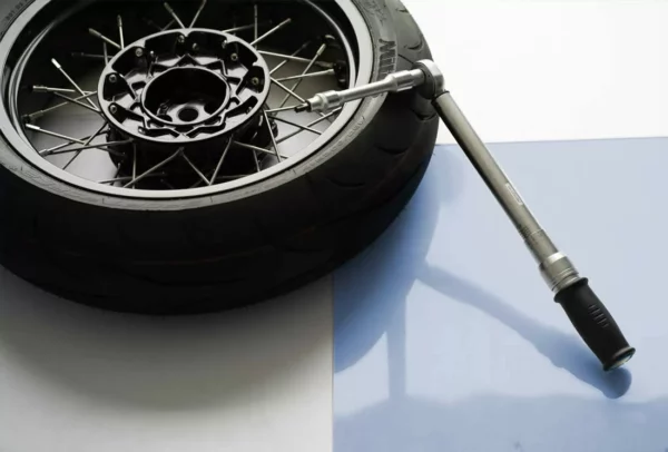 Roue de moto avec clé dynamométrique sur fond clair.
