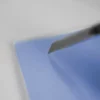 Cutter coupant feuille bleue sur surface blanche.