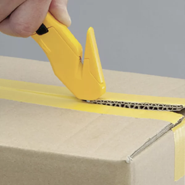 Main utilisant un cutter jaune sur carton