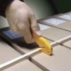 Main coupant un cerclage sur cartons