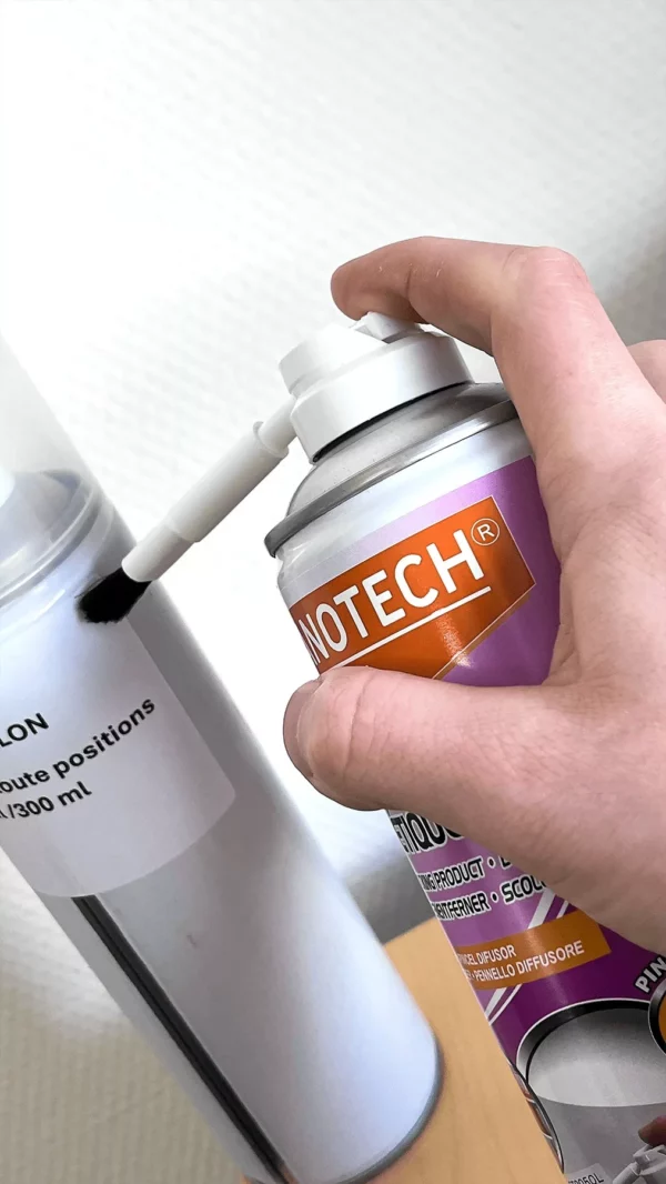Main utilisant bombe aérosol avec pinceau diffuseur